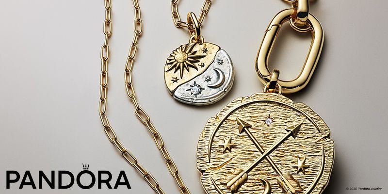 Close-up of three gold Pandora necklaces. The charms have sun/moon and arrow designs.