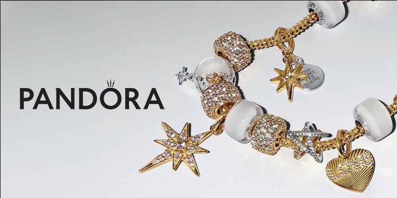 Pandora logo next to a gold and silver charm bracelet with star and heart charms on a white background.
