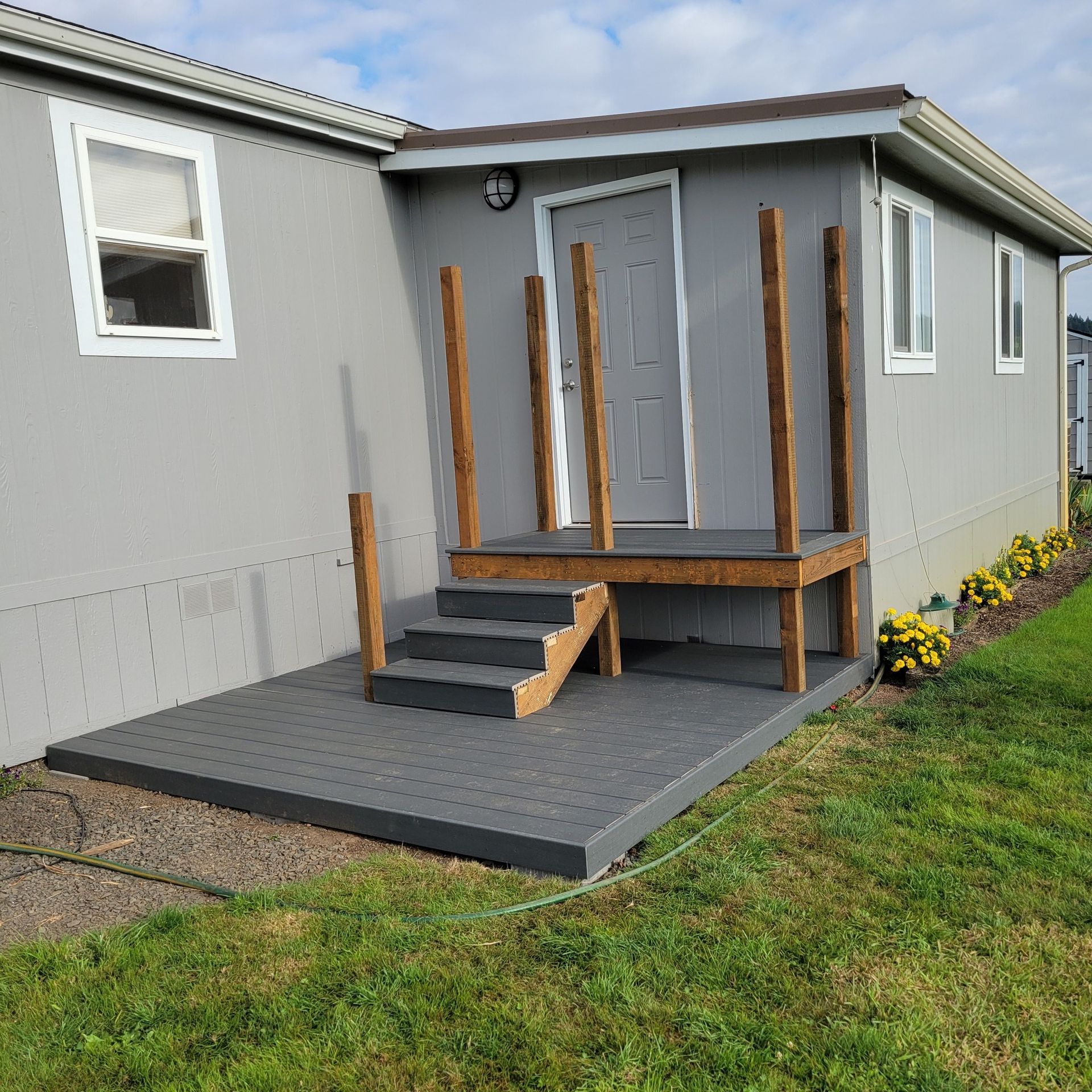A mobile home with a porch and stairs in front of it.