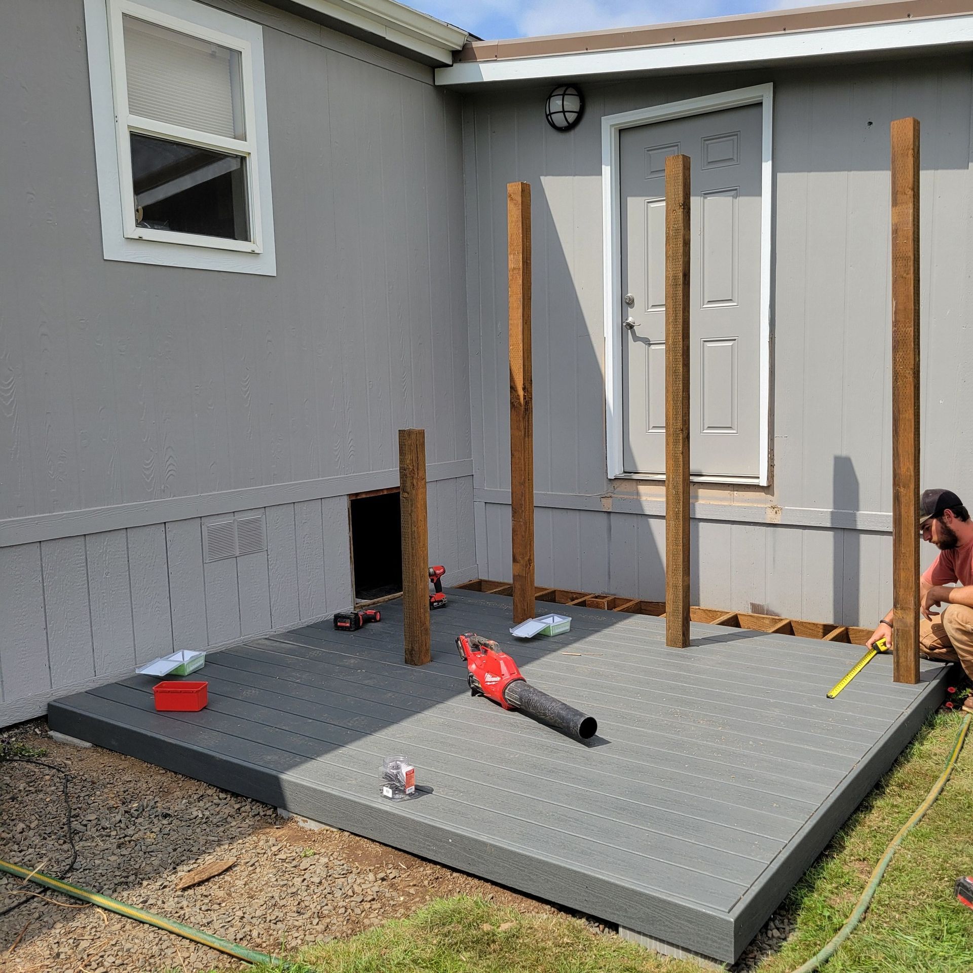 A man is working on a deck in front of a mobile home.