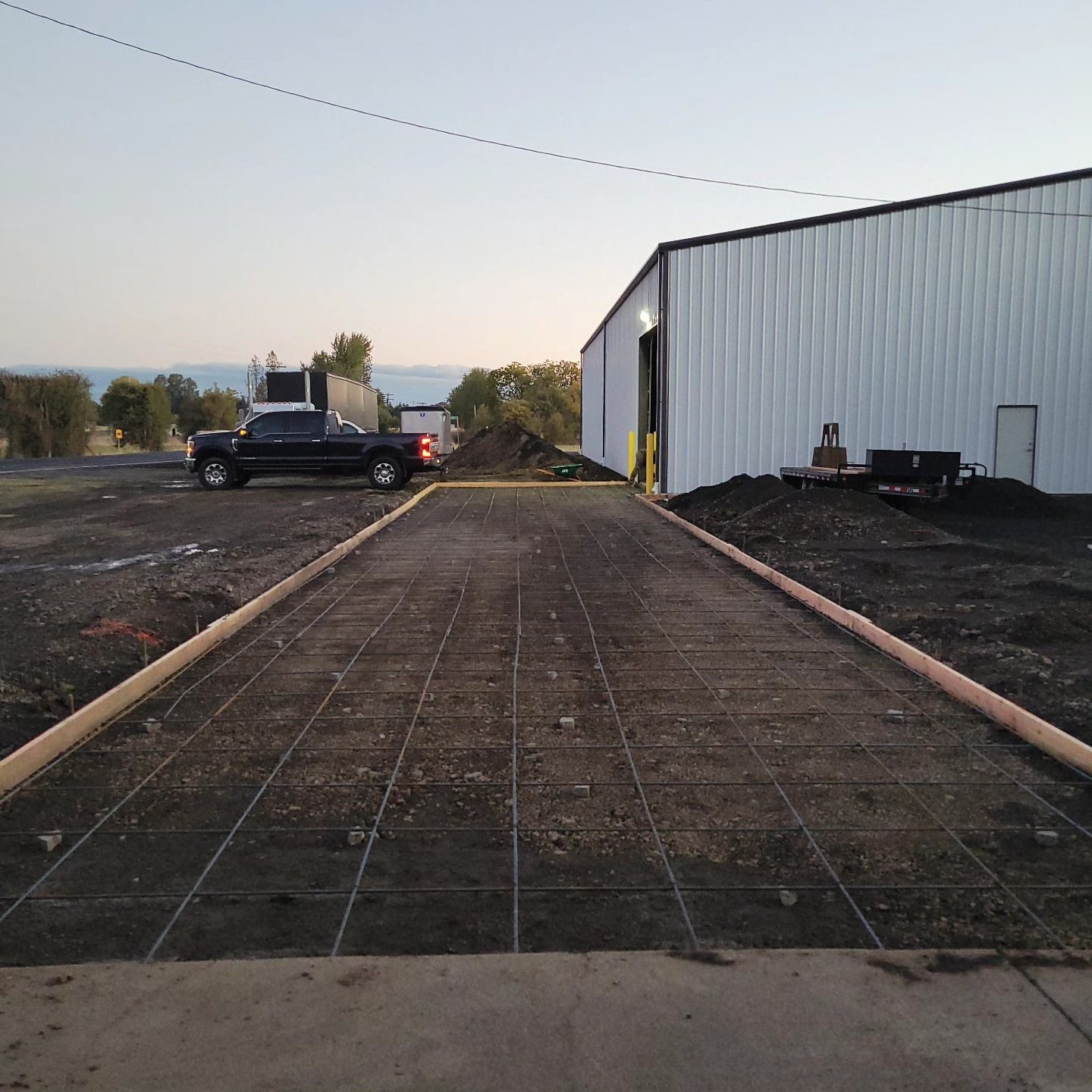 A truck is parked on a dirt road in front of a building