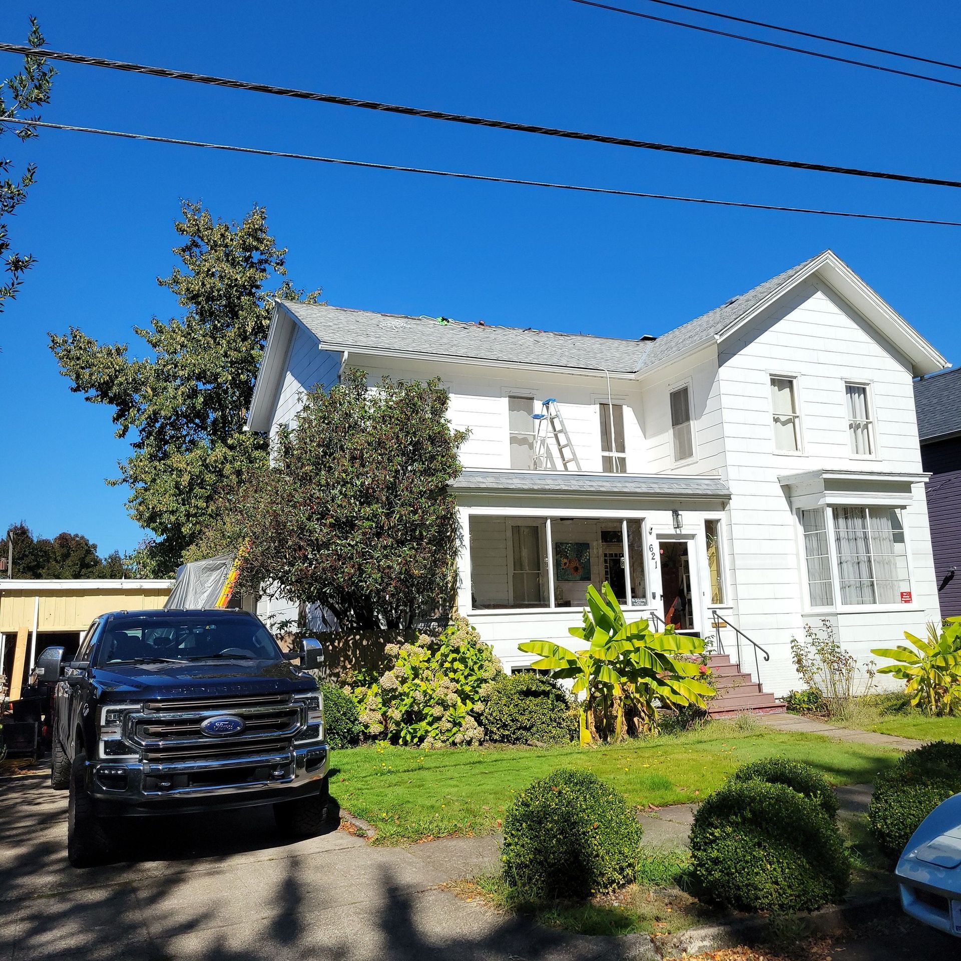 A black truck is parked in front of a white house