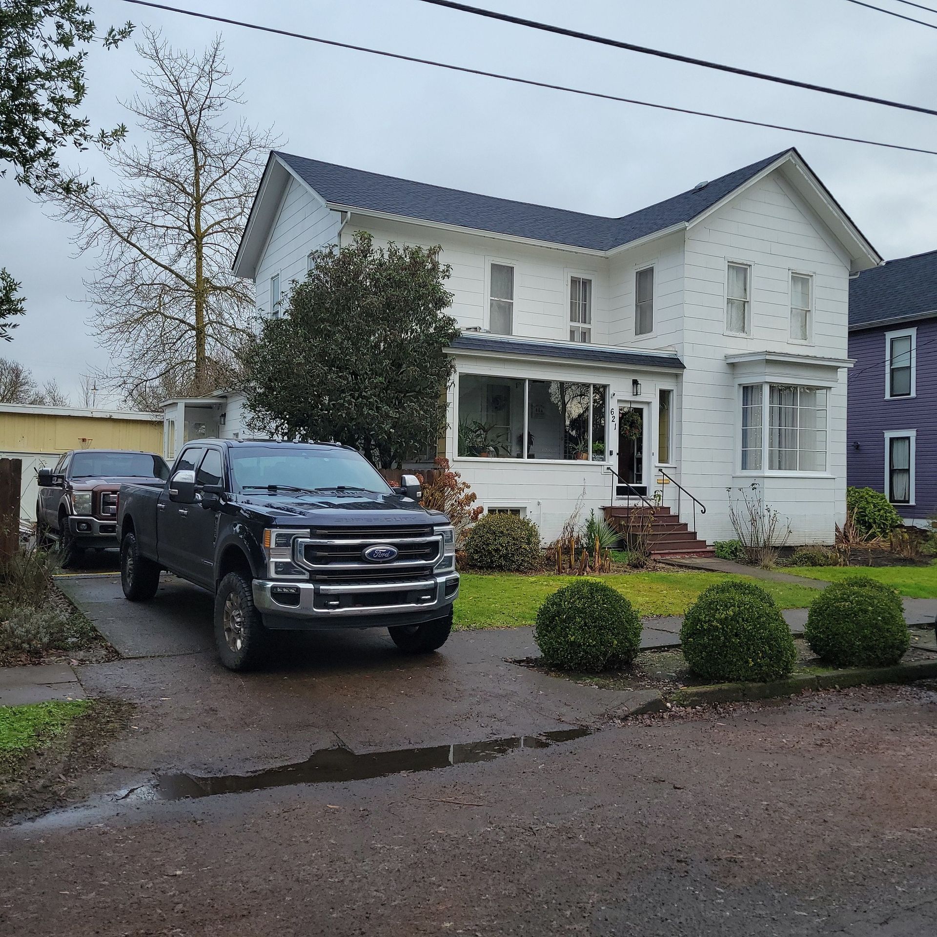 A black ford truck is parked in front of a white house