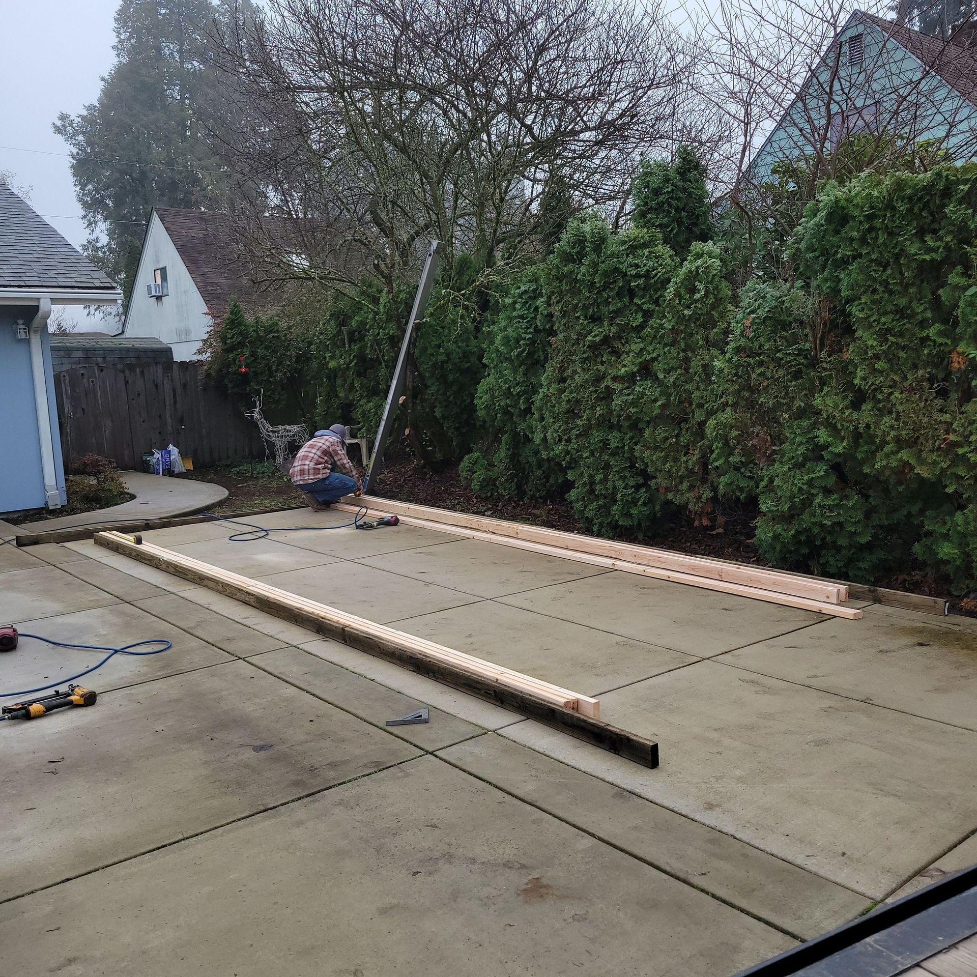 A man is working on a concrete driveway with wooden beams.