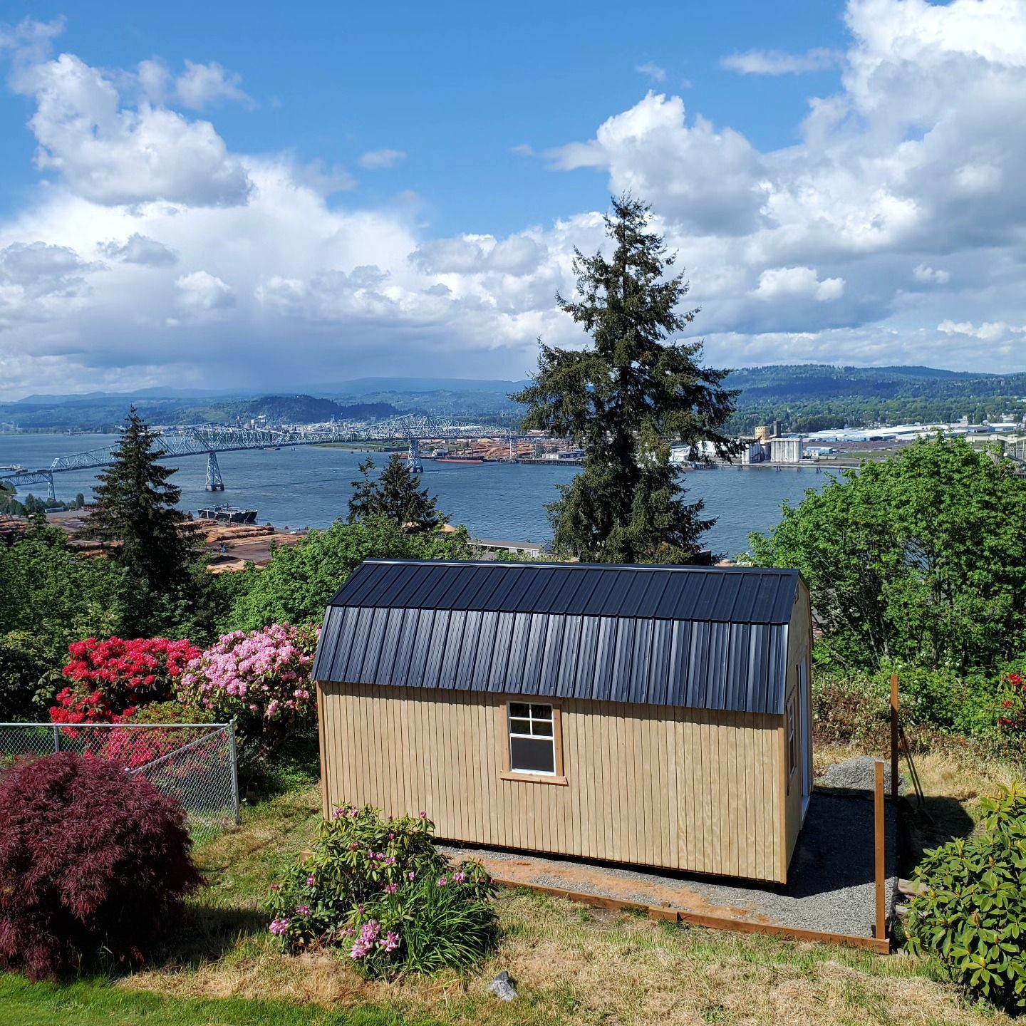 A small wooden shed is sitting on top of a hill overlooking a body of water.