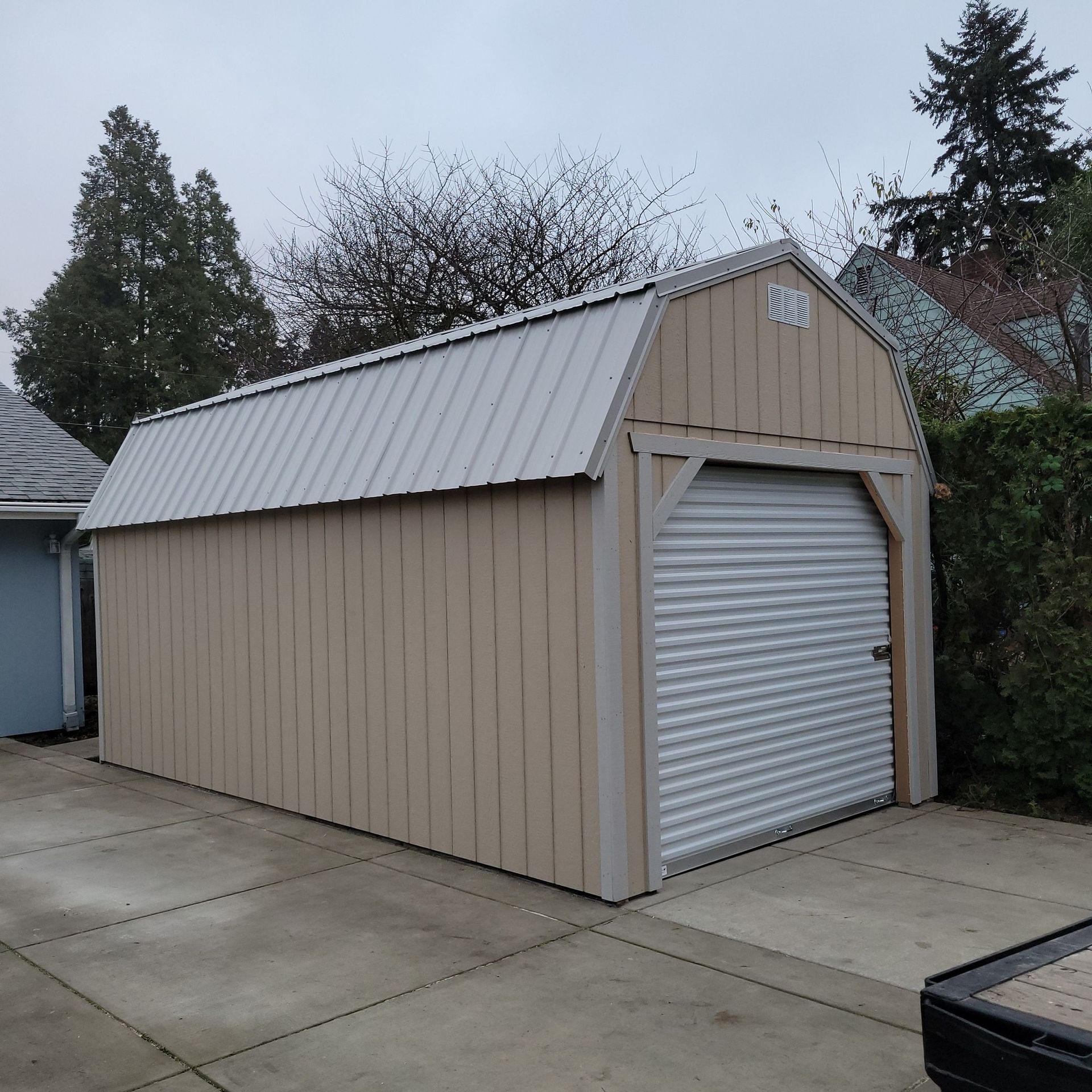 A tan garage with a white roof and a roll up door