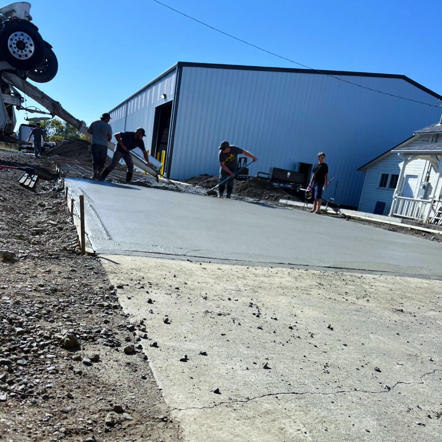 A group of men are working on a concrete driveway in front of a building