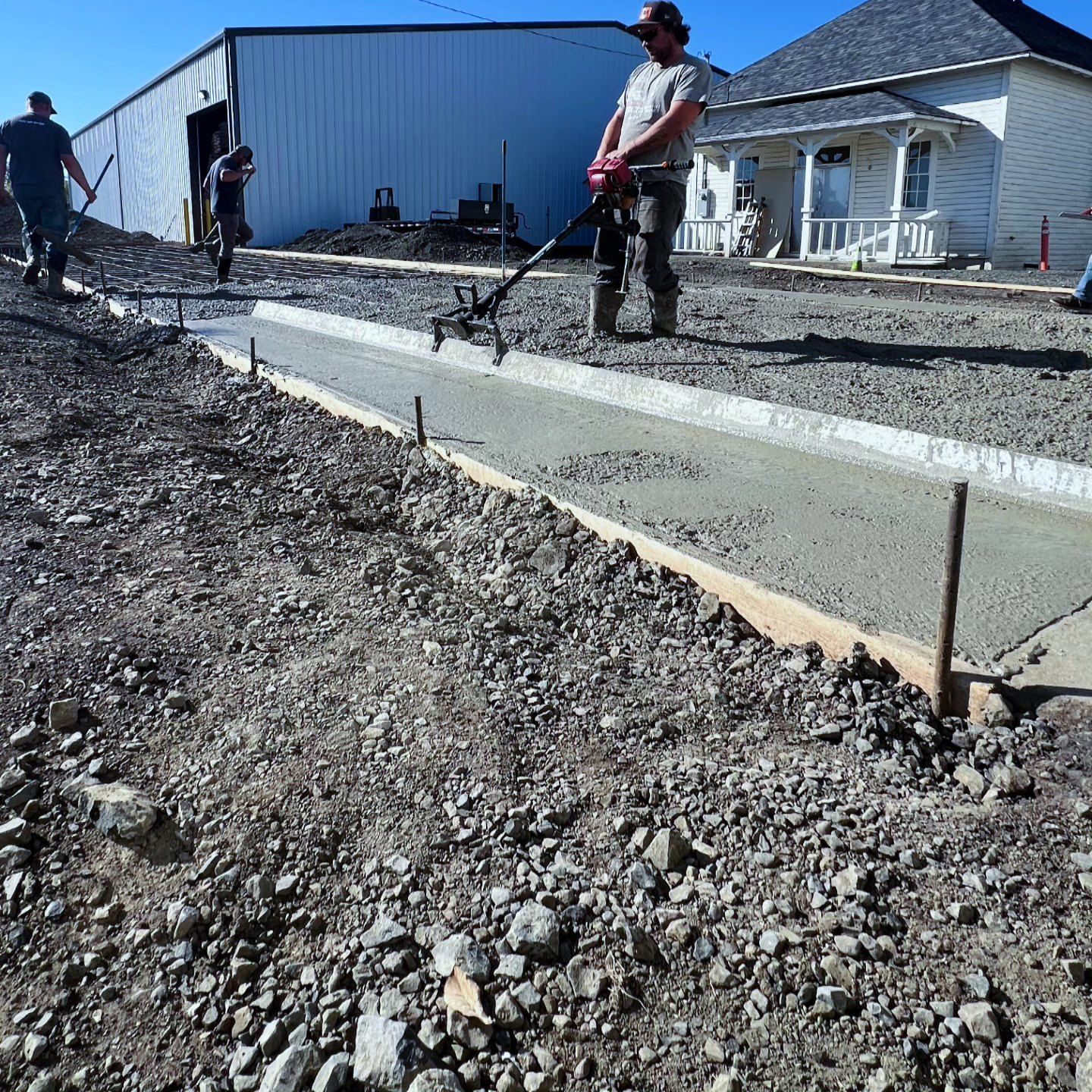A group of men are working on a sidewalk in front of a house.