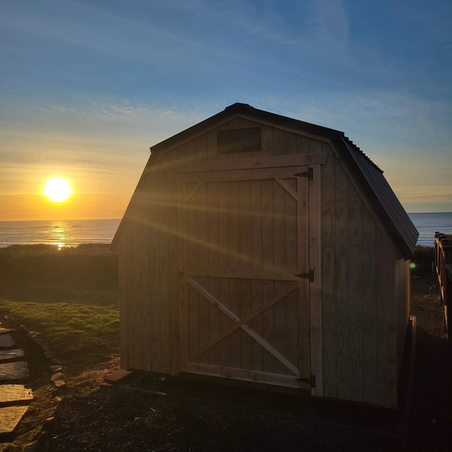 A barn shed with the sun setting in the background