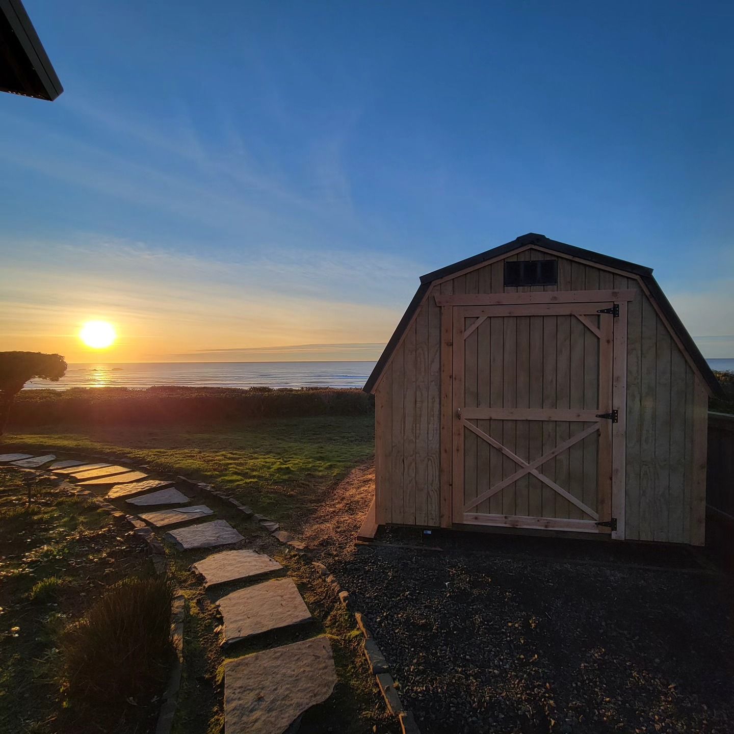 A wooden barn with a sunset in the background