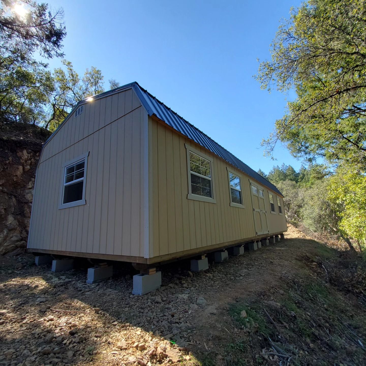 A small house is sitting on top of a dirt hill.