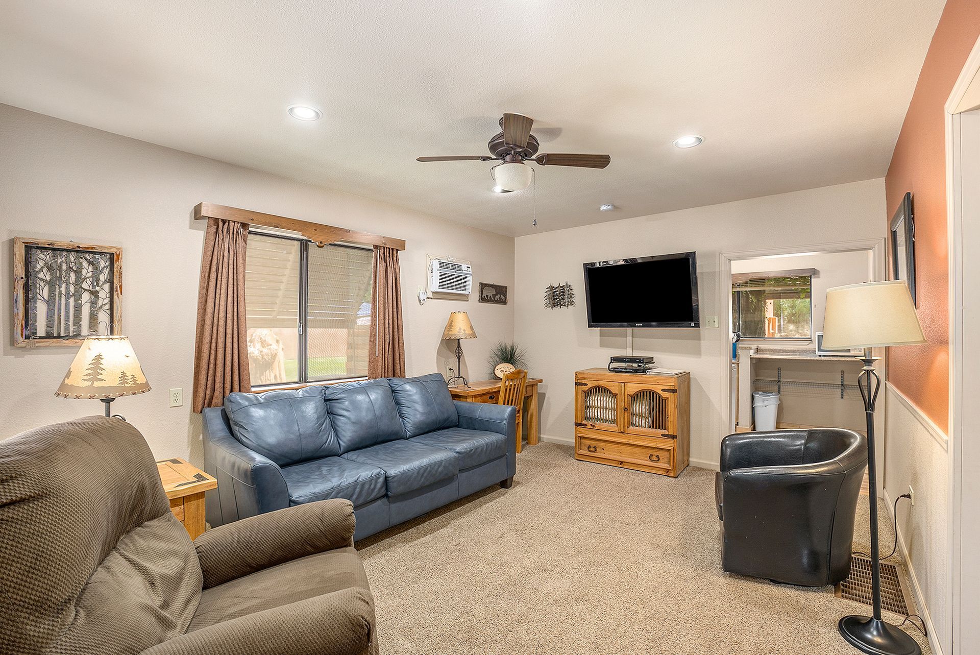 A living room with a sleeper sofa couch , chairs , and a flat screen tv.