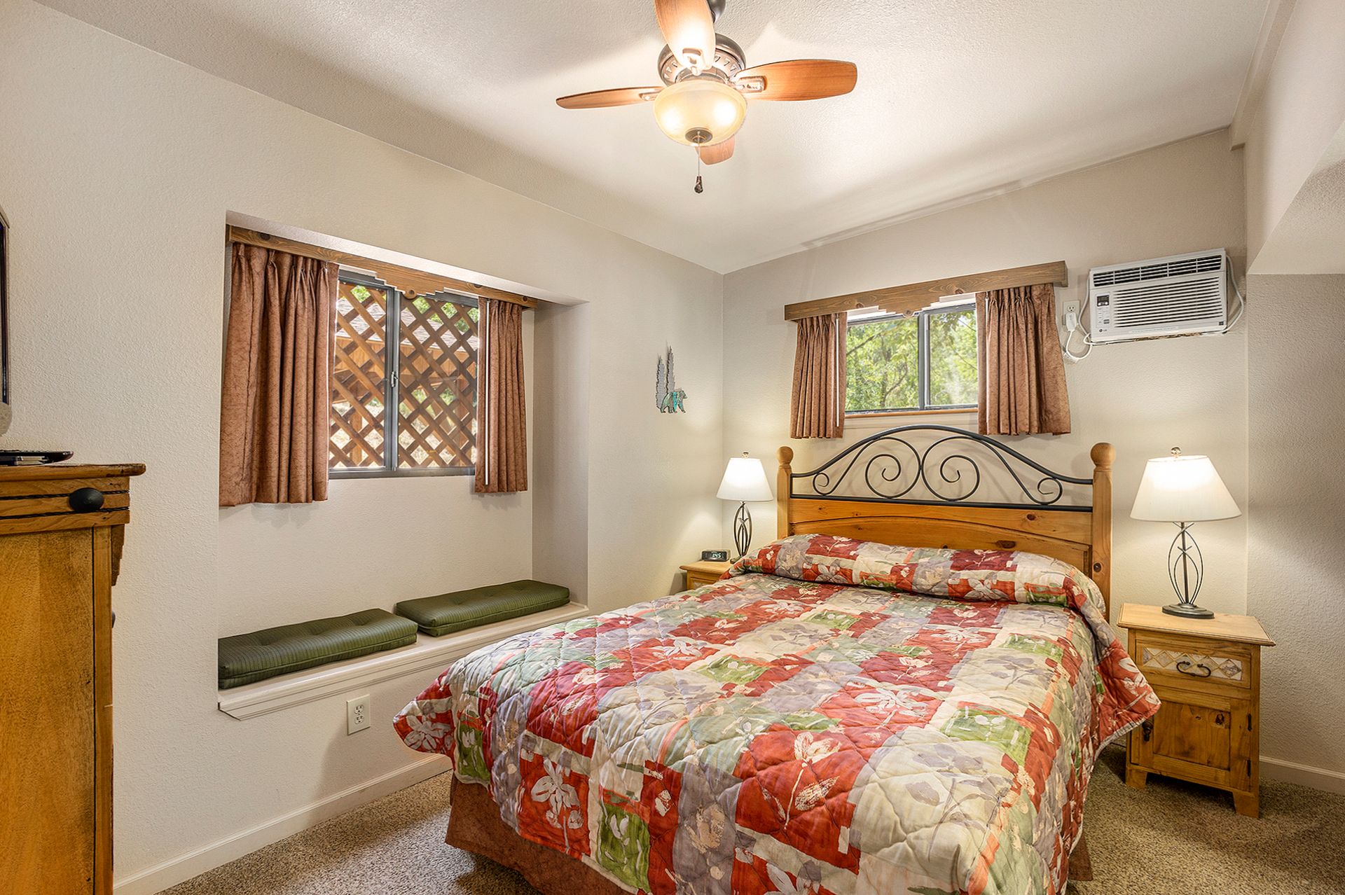 Bedroom with a bed, two lamps, windows with curtains, and a ceiling fan.