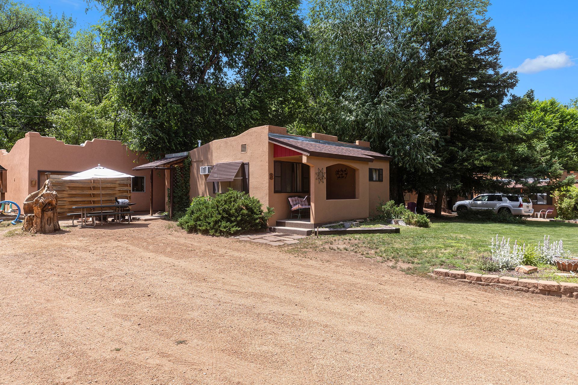 A small house is sitting in the middle of a dirt field.