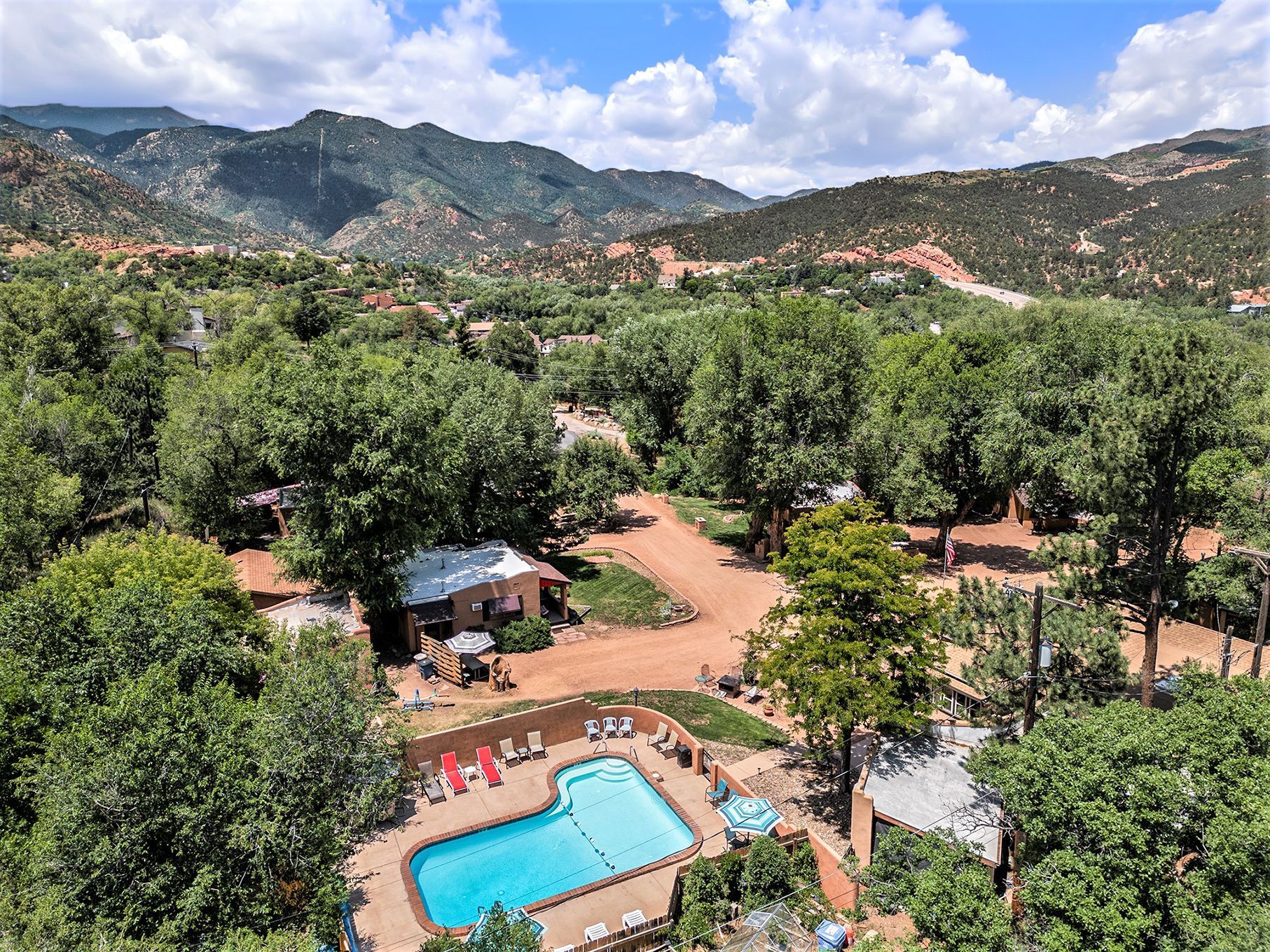 An aerial view of a swimming pool surrounded by trees and mountains.