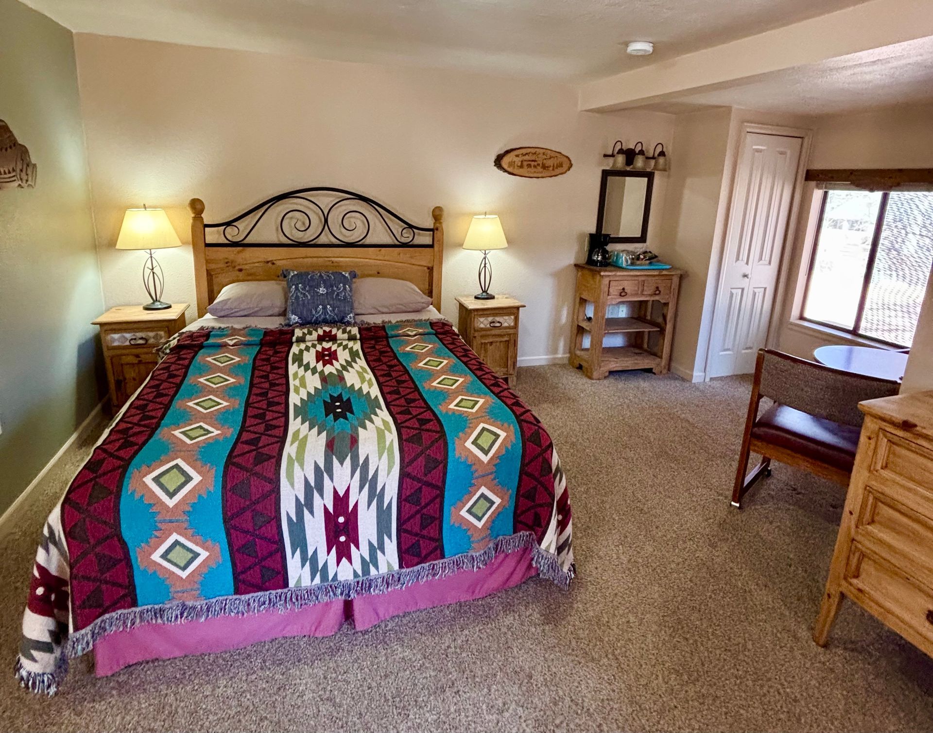 Bedroom with a king-size bed, nightstands, and a dresser. The bed has a colorful southwestern-style blanket.