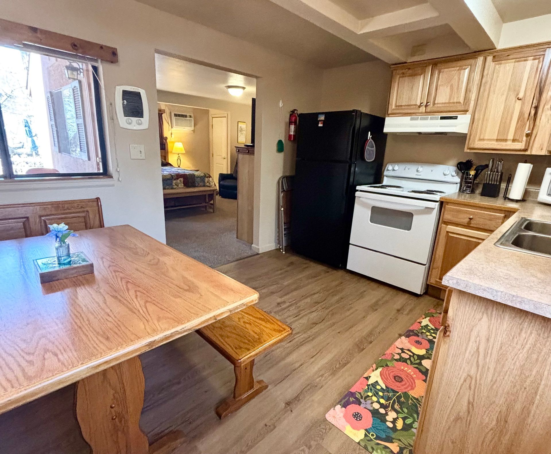 Kitchen with dining table, stove, and a doorway leading to a living room.