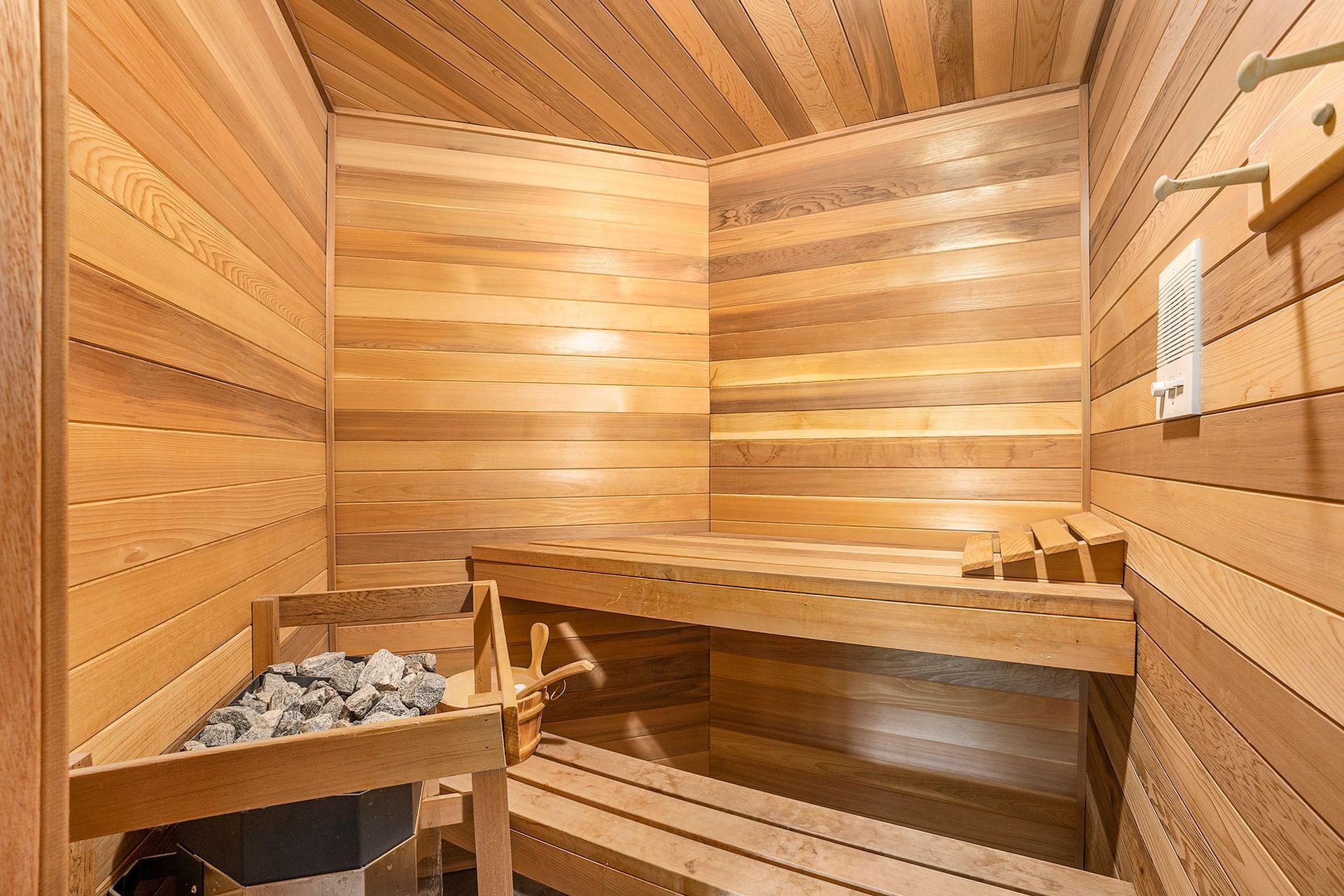 A wooden sauna with two benches and a heater.