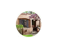 A cartoon illustration of a house in a circle on a white background.