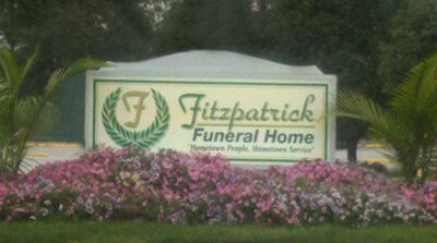 a sign for Fitzpatrick Funeral Home is surrounded by flowers