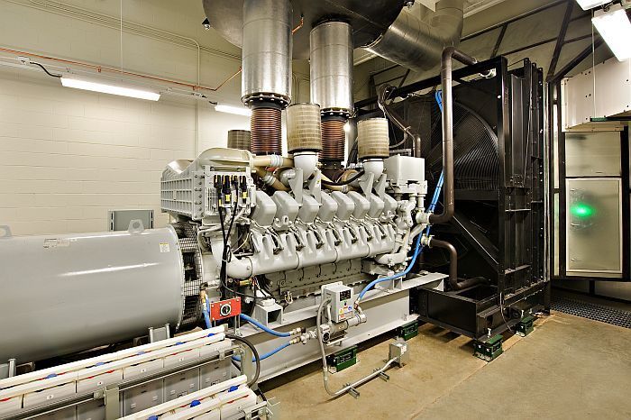 A large engine is sitting in a room with a green light on the wall.