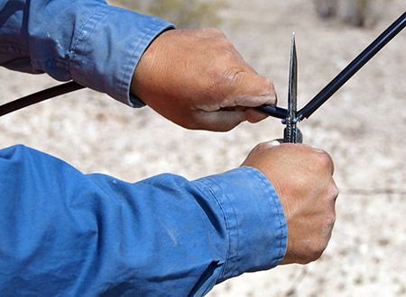 A person is cutting a wire with a pair of scissors.