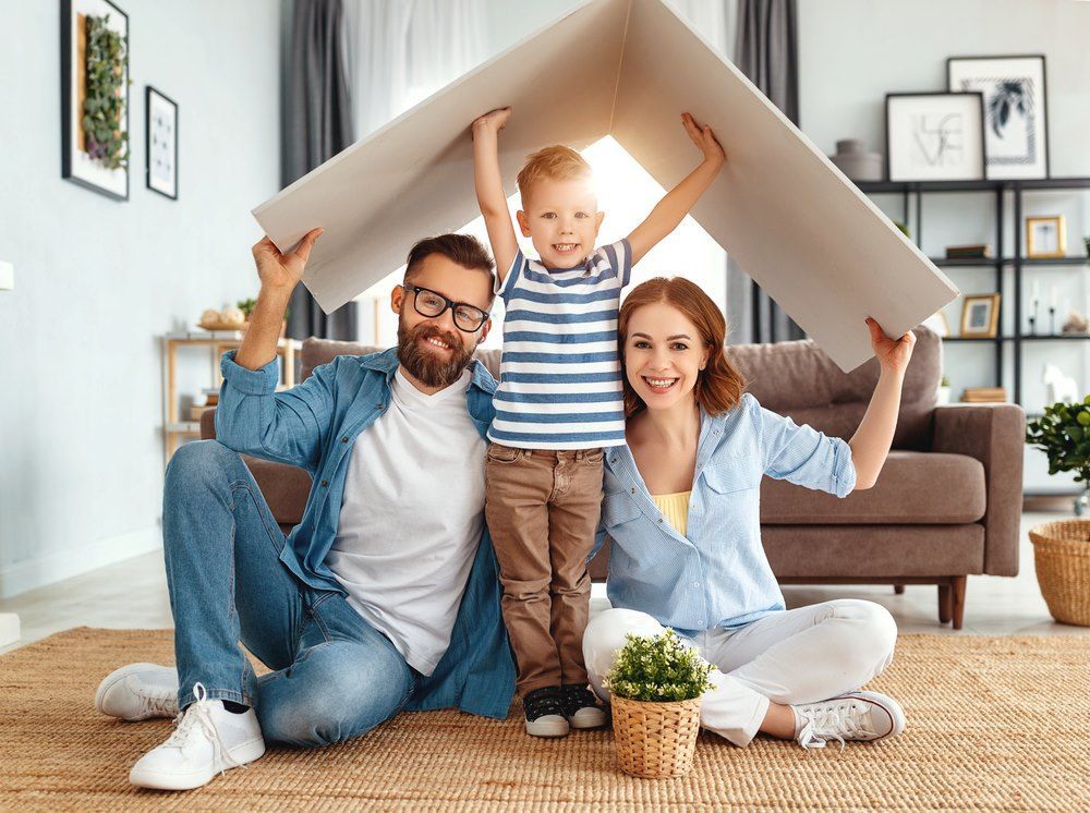 A Family is Sitting on the Floor Under a Cardboard House — Maitland Central Podiatry in Maitland NSW
