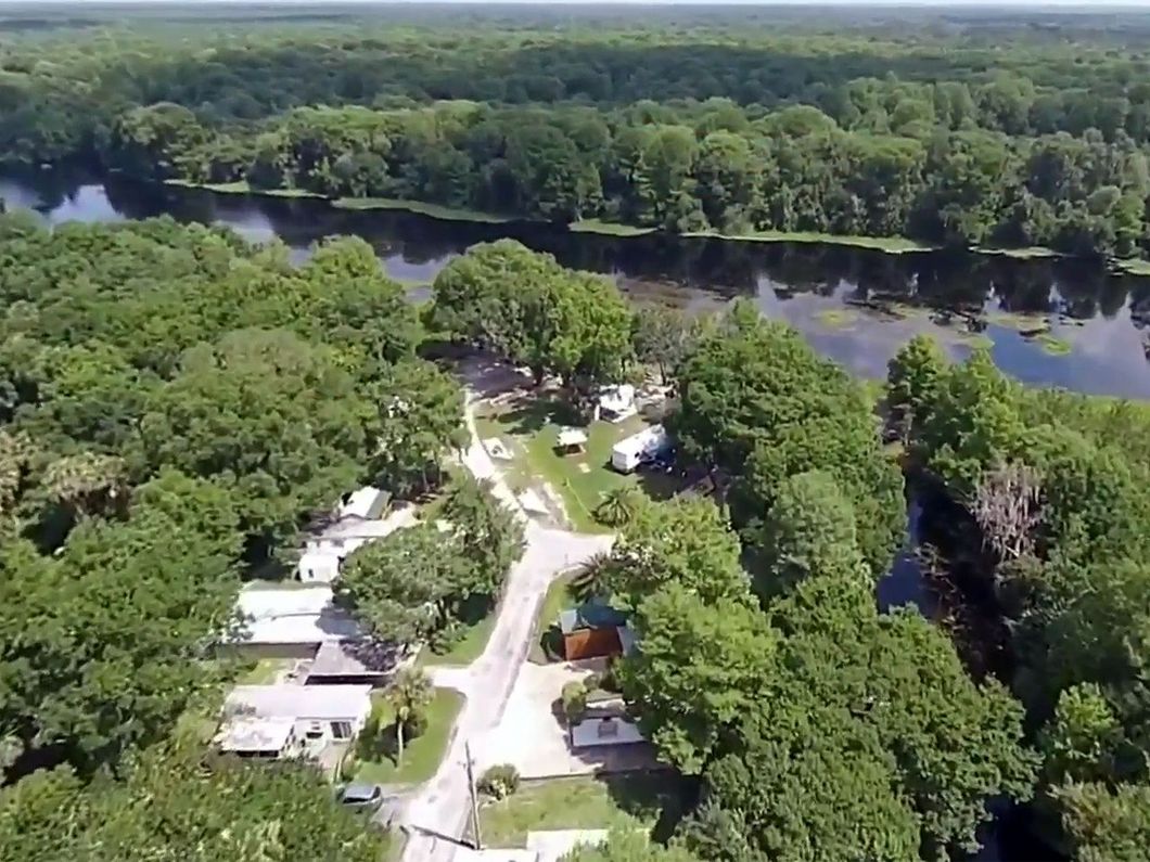 an aerial view of a river surrounded by trees and houses