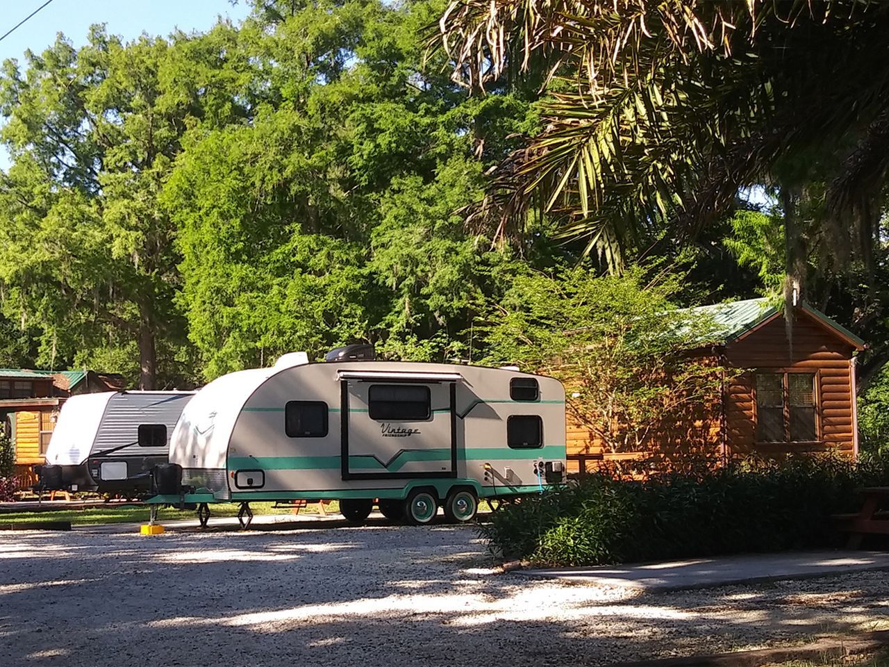 a vintage trailer is parked in front of a log cabin