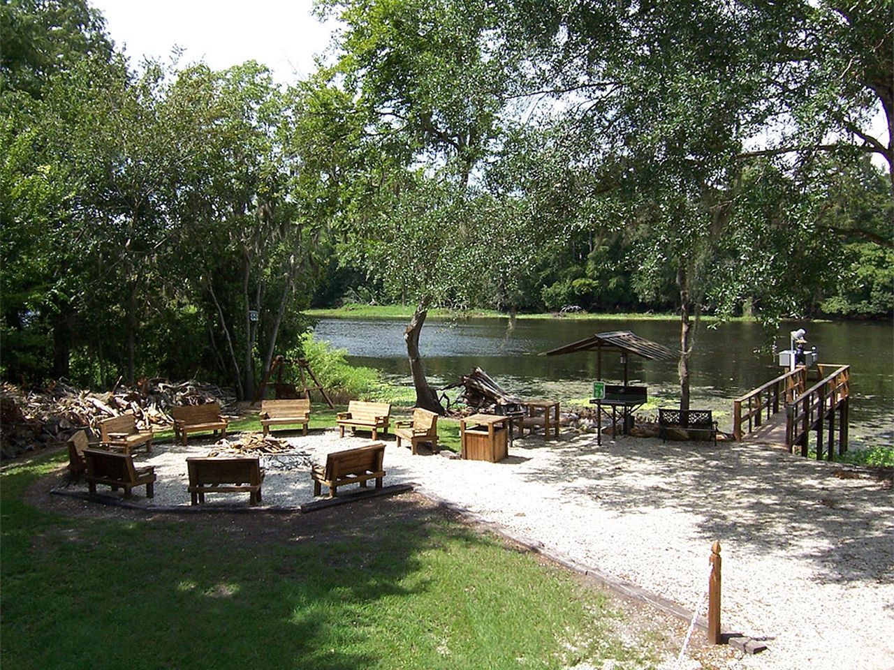 a fire pit sits in the grass near a lake