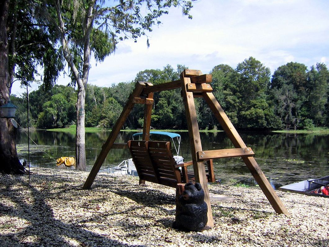 a wooden swing sits in front of a lake