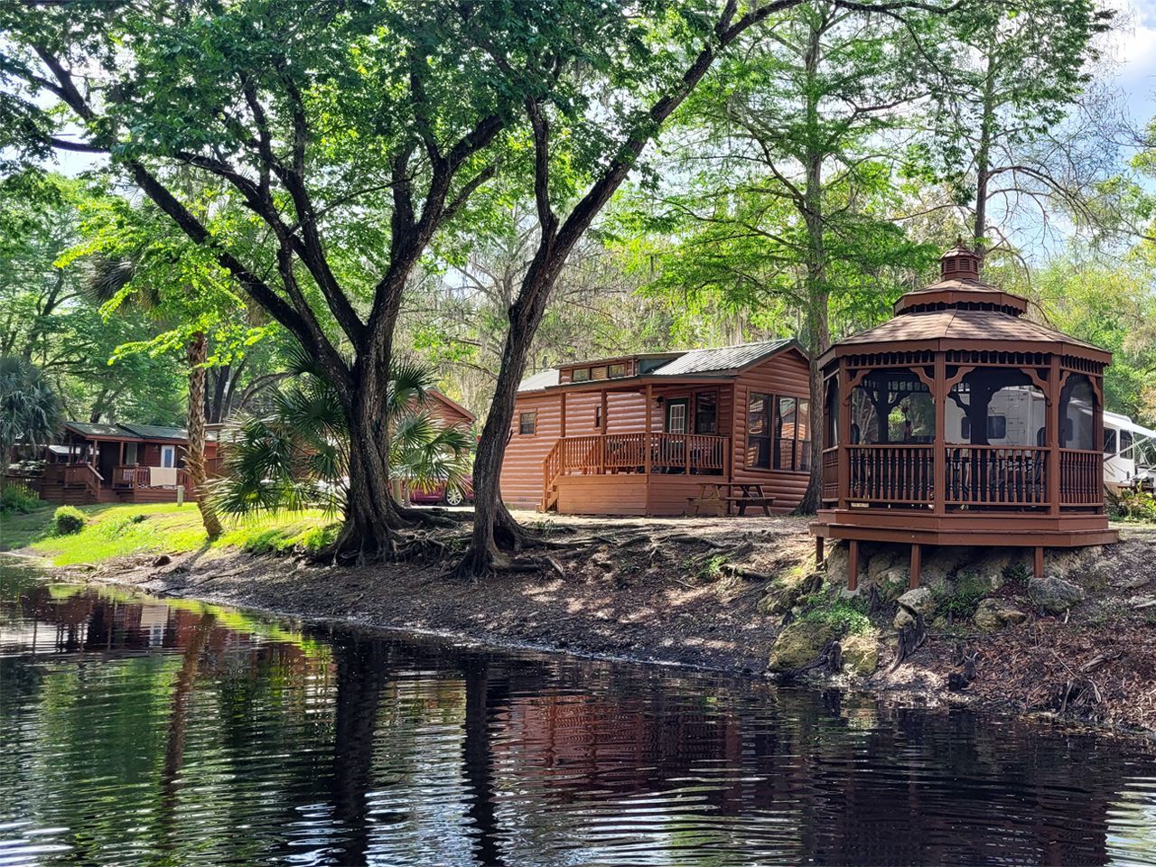 a gazebo sits on the shore of a body of water