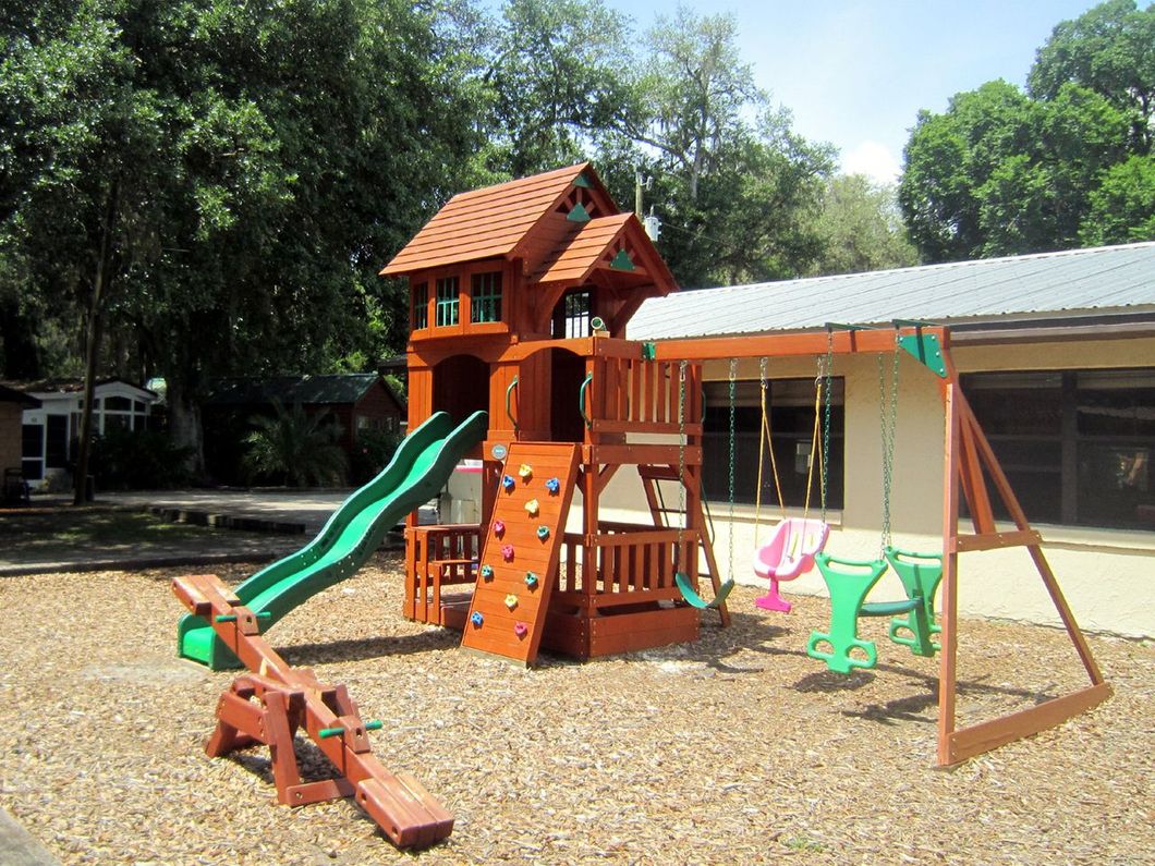 a playground with a slide and swings in front of a building