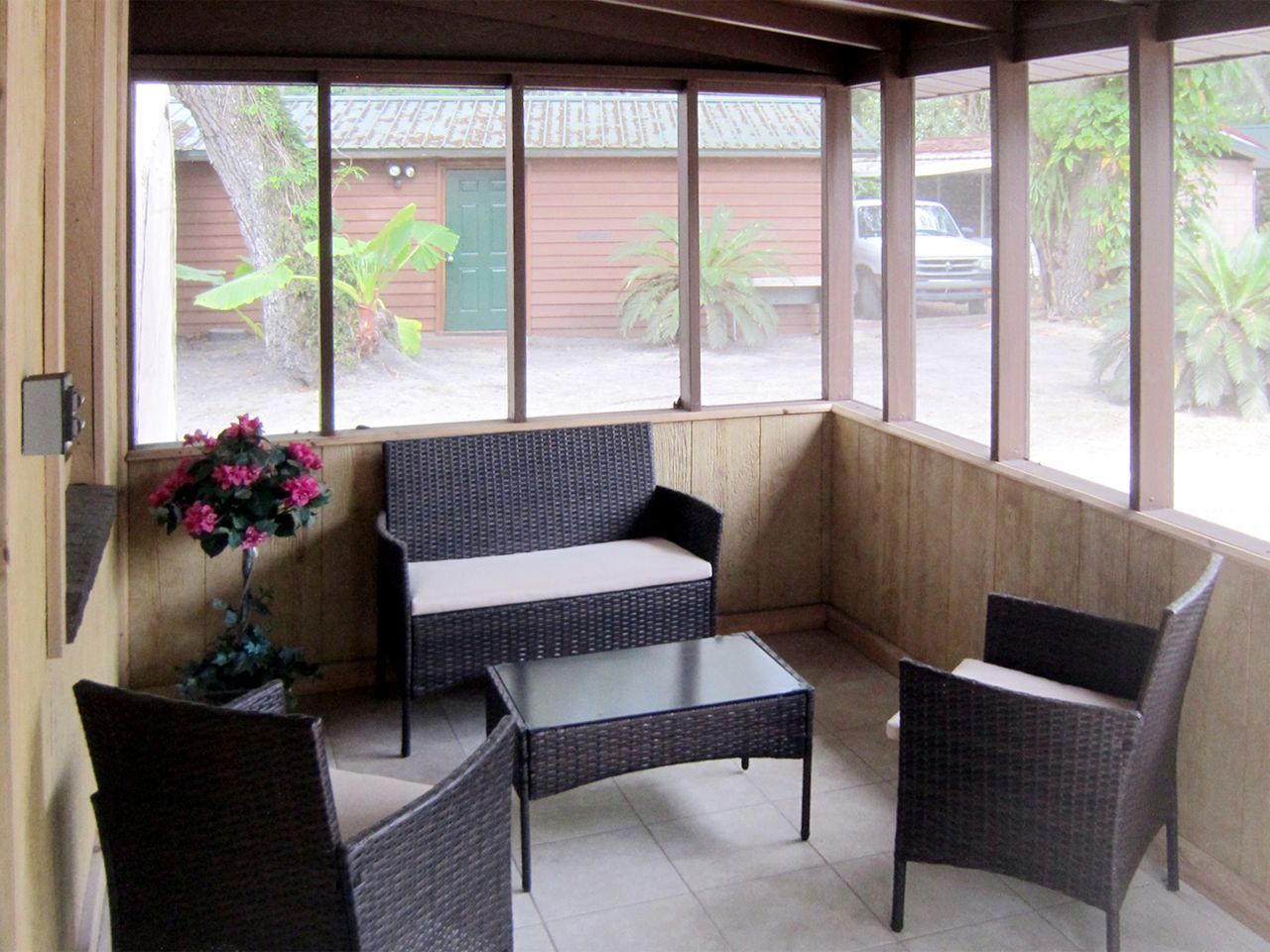 a screened in porch with wicker furniture and a table