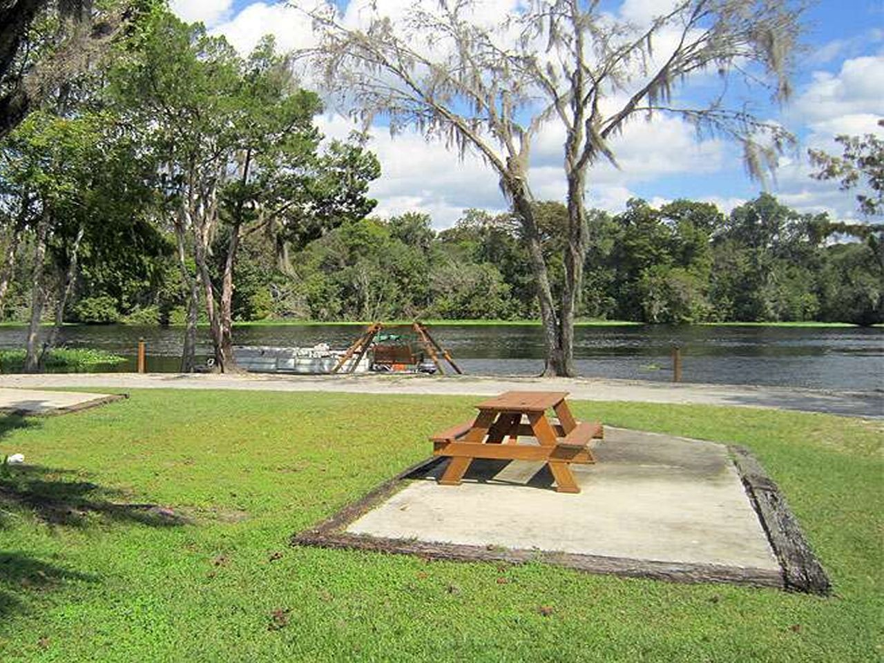 a picnic table is sitting in the grass next to a lake .