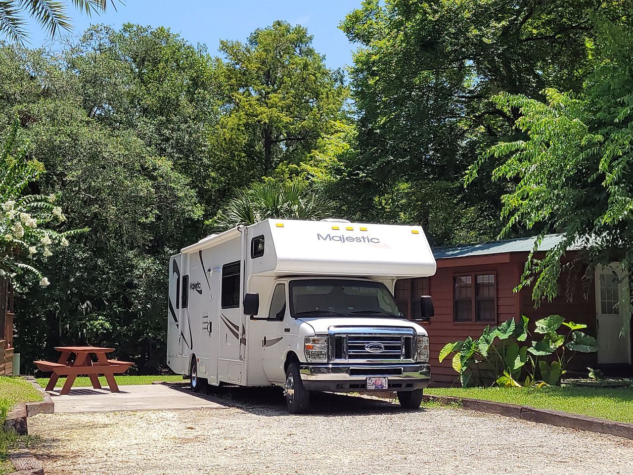a white rv is parked on a gravel road in front of a house .
