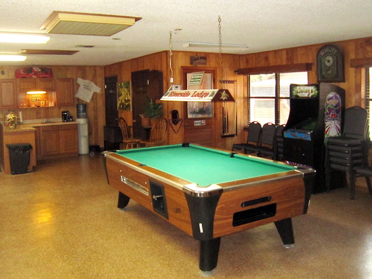 a pool table in a room with a budweiser sign above it