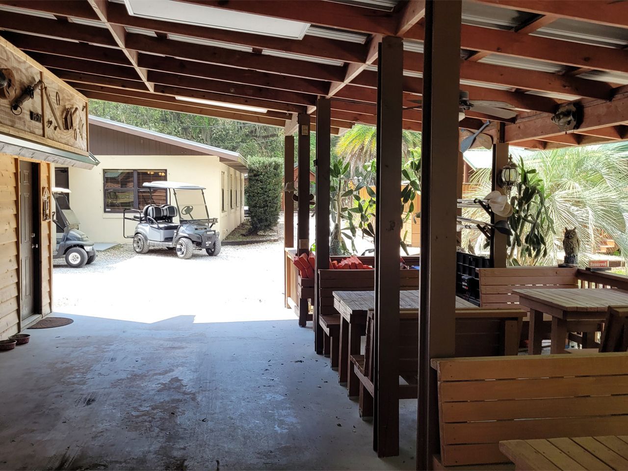 a covered area with tables and chairs and a golf cart parked in the background