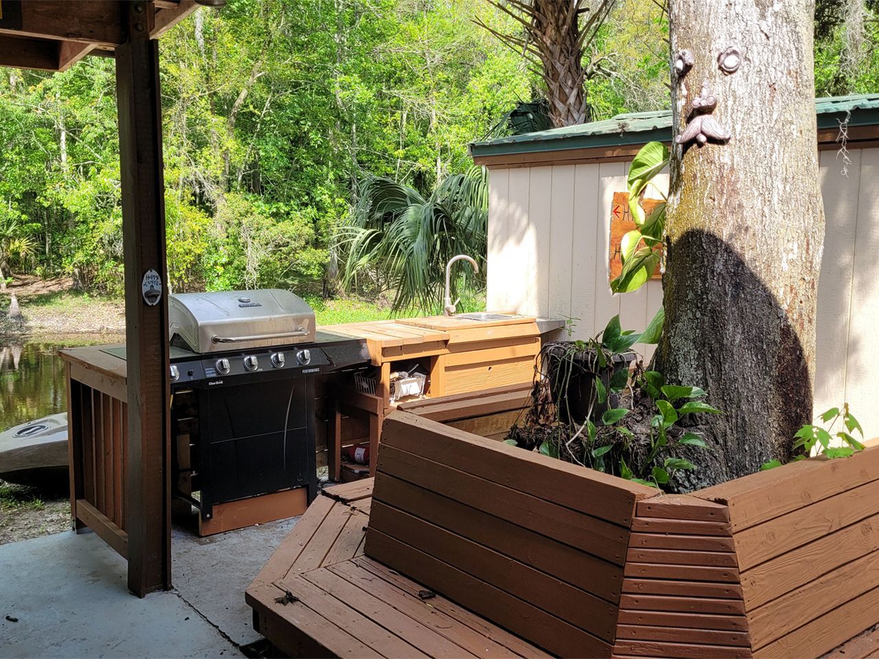 a grill is sitting on a wooden deck next to a tree .
