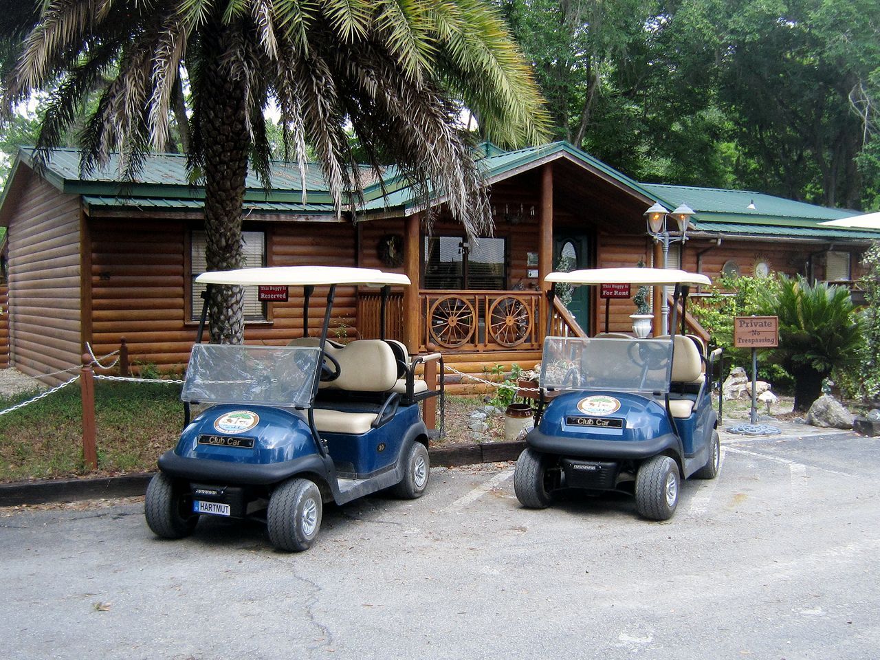 two golf carts are parked in front of a log cabin