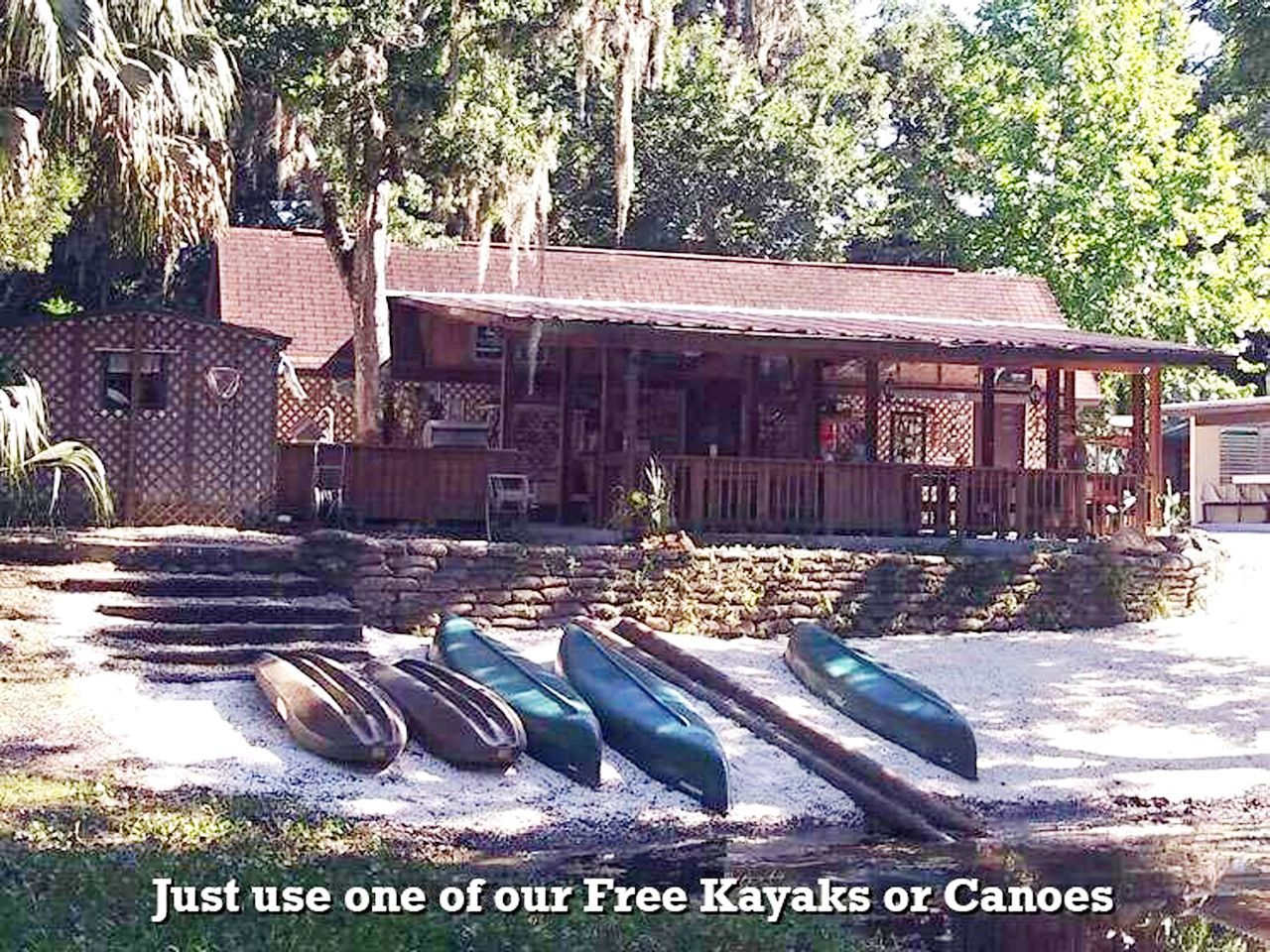 a row of canoes are lined up in front of a house that says just use one of our free kayaks or canoes