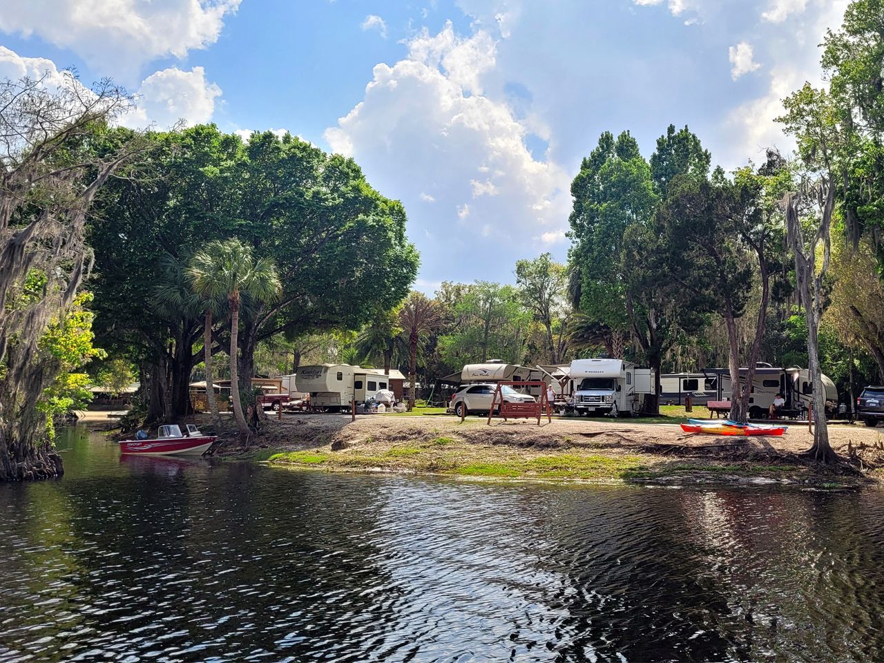 a row of rvs are parked next to a body of water .