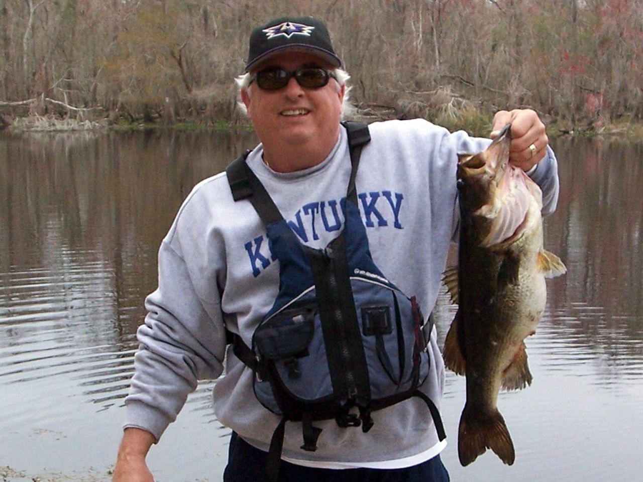 a man wearing a kentucky shirt is holding two fish