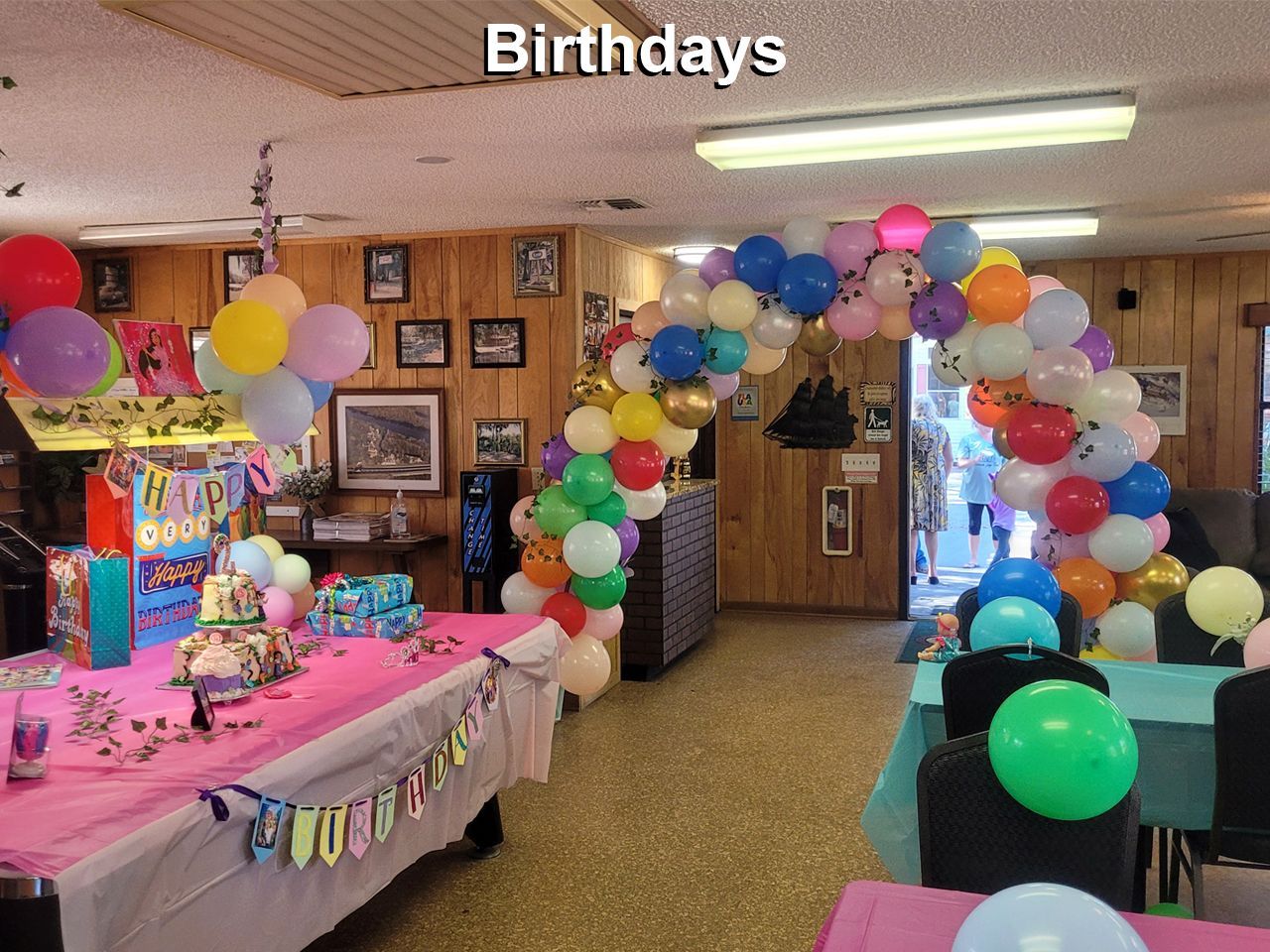 a room decorated with balloons and a sign that says birthdays