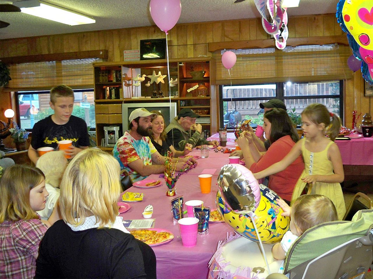 a group of people are sitting at a table with balloons on it