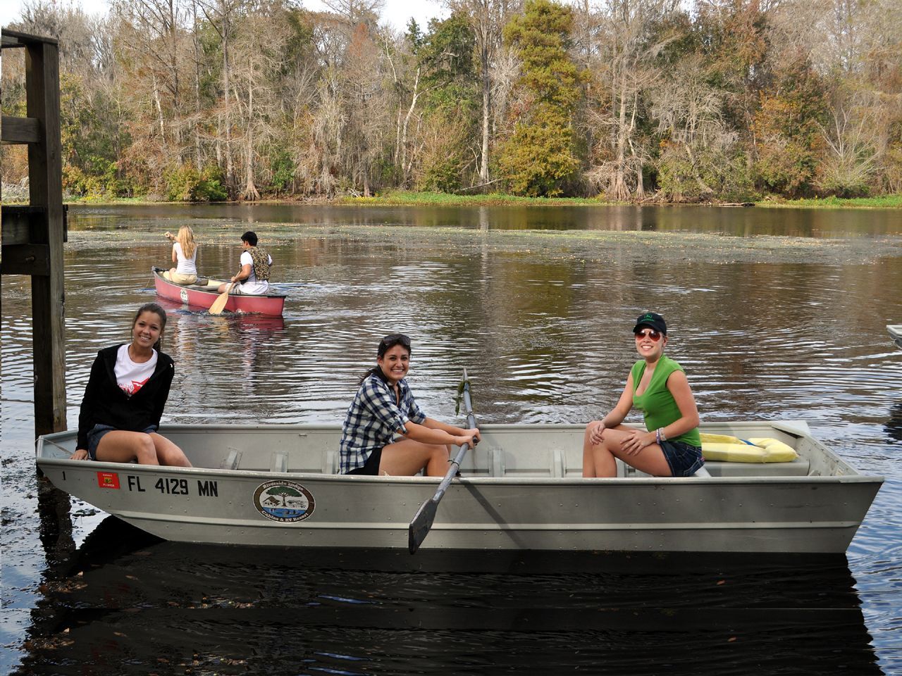 three people are sitting in a boat with the license plate fl 4775