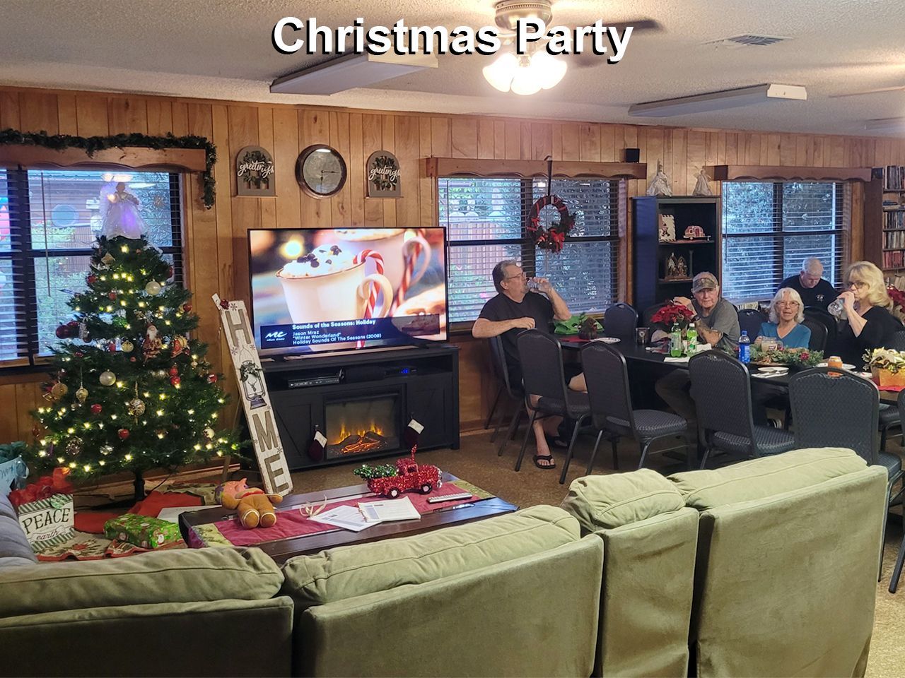 a group of people are gathered in a living room for a christmas party .