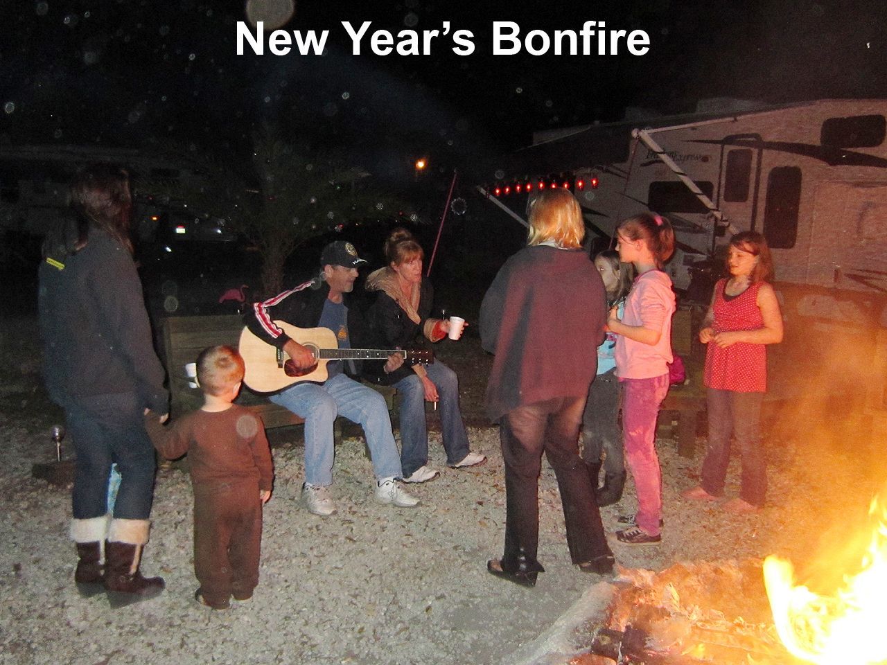a group of people gathered around a bonfire with the caption new year 's bonfire