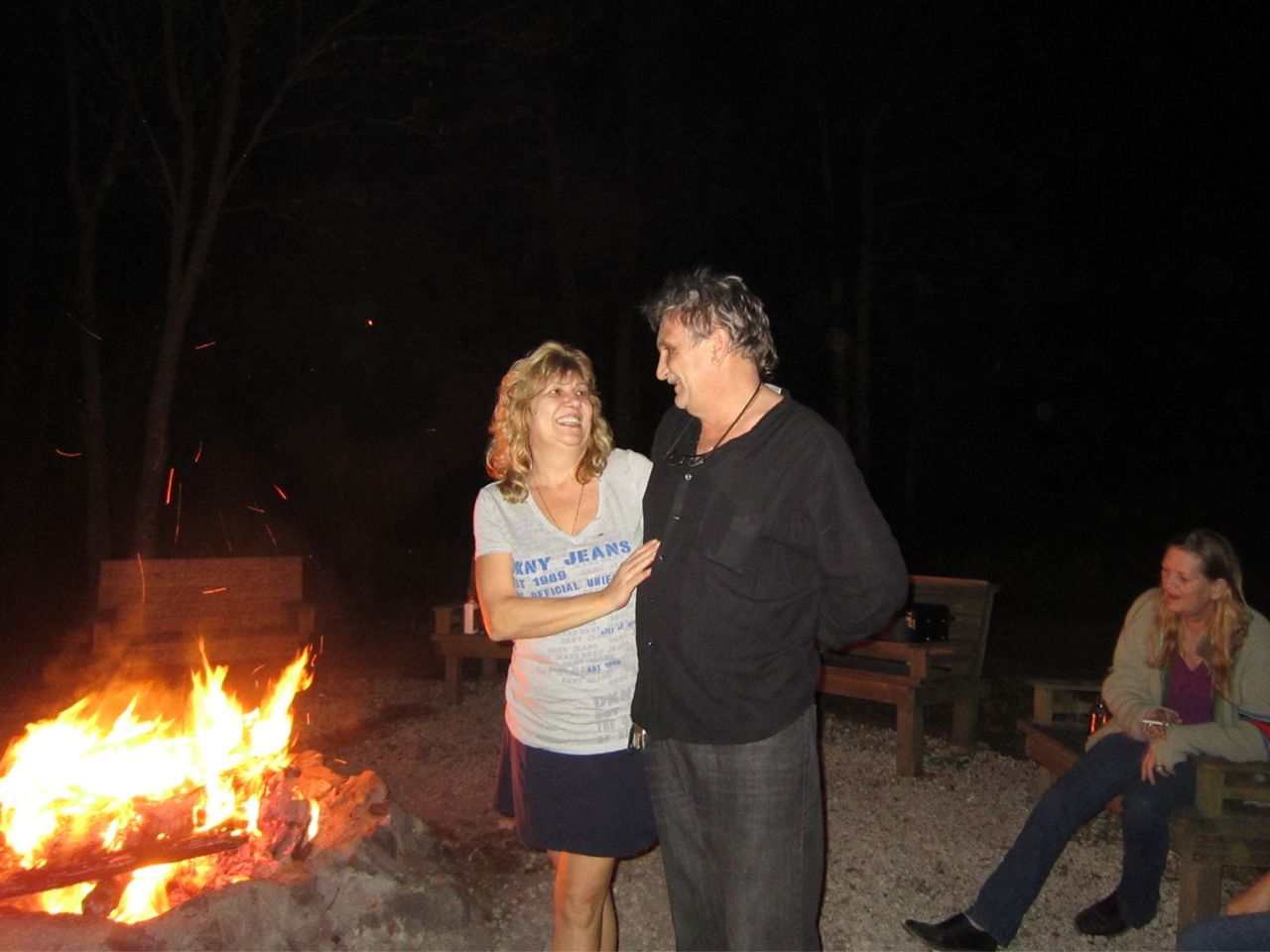 a man and a woman are standing in front of a fire pit