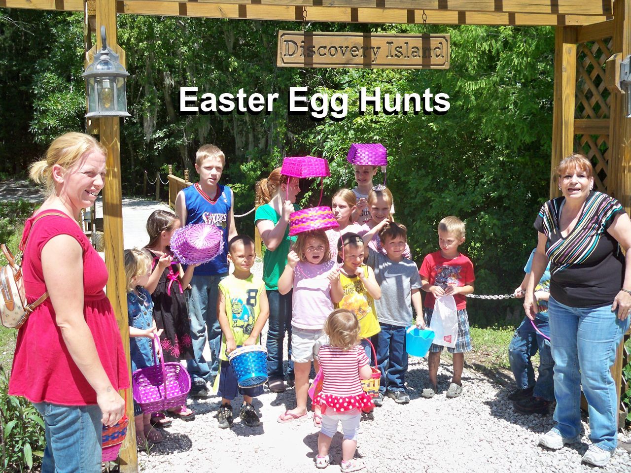 a group of children are standing in front of a sign that says easter egg hunts
